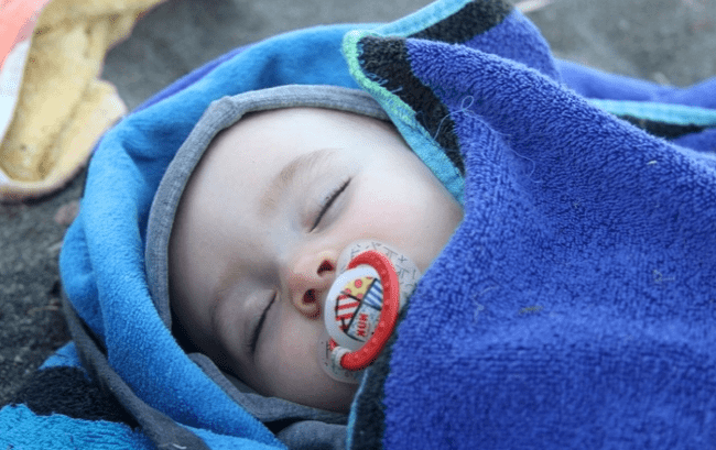 bebé-durmiendo-con-un-chupete-de-silicona-en-la-boca-tapado-con-una-toalla-azul